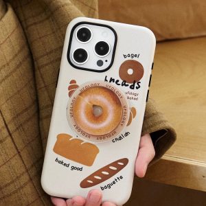 Cream bakery-print case held upright with the golden bagel grip clipped to its center