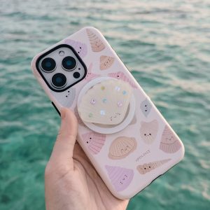 The pastel shell case held up against turquoise sea water