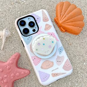 The case lying on wet sand beside a starfish, conch and orange shell dish