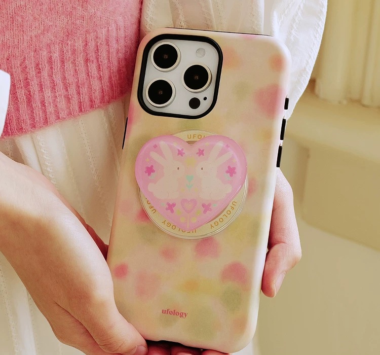 Soft pink and green case held in both hands beside a pink knit