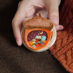 Hand holding the acorn grip against a brown knit blanket