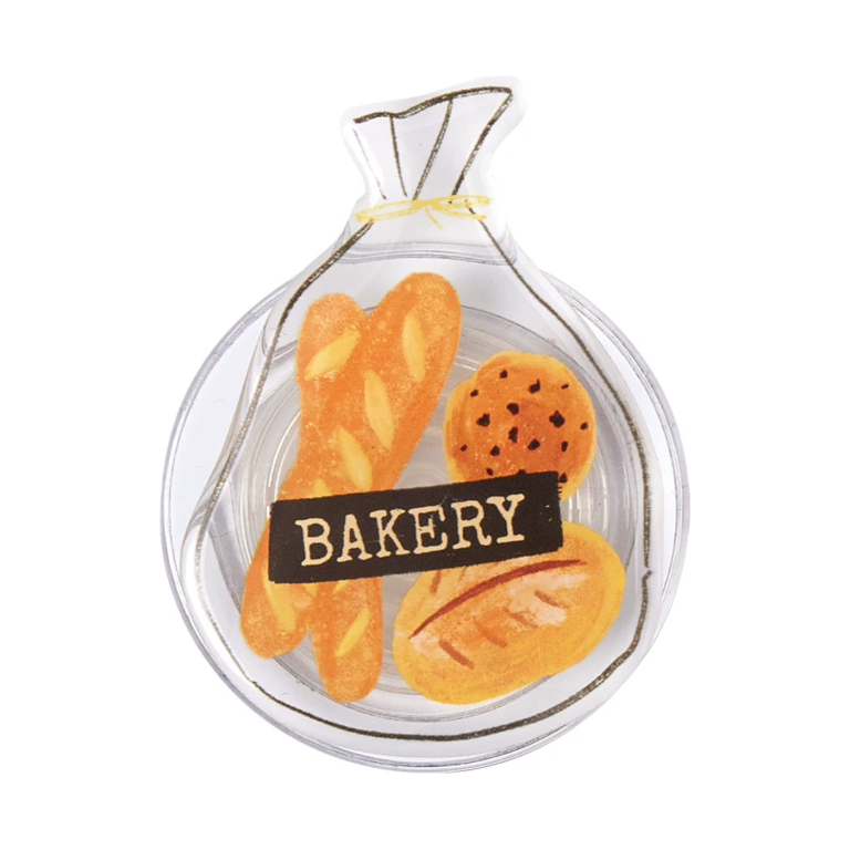 Bakery bag MagSafe phone grip, a clear bag of baguettes and a cookie with a Bakery label