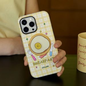 Hand holding the yellow check breakfast case with the fried egg holder at a cafe table