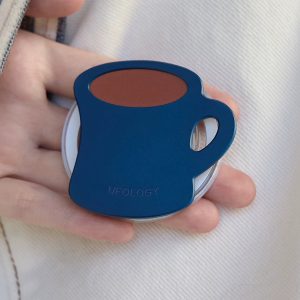 Hand holding the coffee mug grip with the brown coffee surface on top