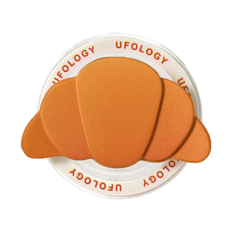 Croissant MagSafe phone grip with a golden layered croissant on a clear round magnetic base