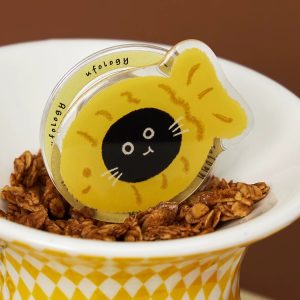 Fish cat grip resting in a bowl of granola on a yellow and white stand