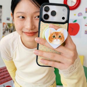 Ginger cat grip on the back of a phone held next to a smiling face