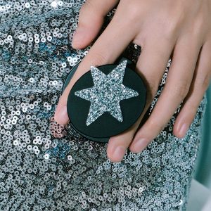 Hand with the glitter star grip over a silver sequin skirt