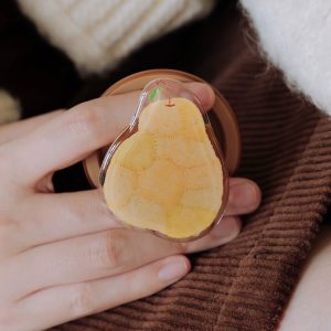 Hand holding the pear grip against a brown knit sleeve