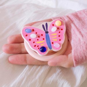 Open hand holding the pink butterfly grip over a white sheet