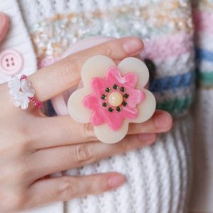 Pink flower grip held over a pastel knit cardigan