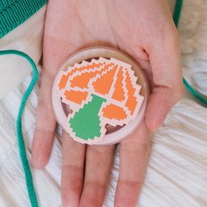 Open hand holding the pixel mushroom grip above a white skirt