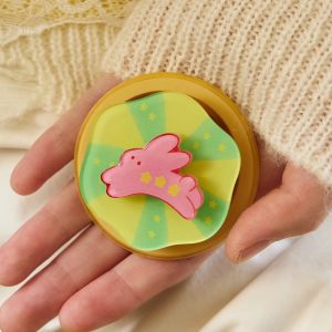 Open hand holding the rabbit flower grip over a cream sweater