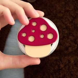 Hands holding the red mushroom grip against a dark brown background