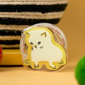 Sad cat grip standing on a yellow table beside a striped basket