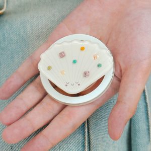 Open hand holding the seashell grip with its colored stones facing up