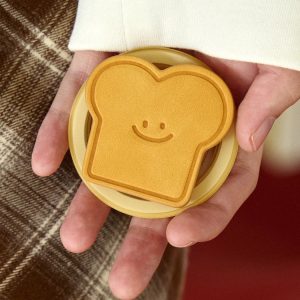 Hands holding the toast grip so the smile and crust are visible